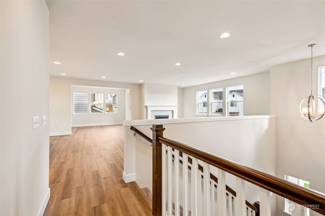 hallway featuring an inviting chandelier and light hardwood / wood-style flooring