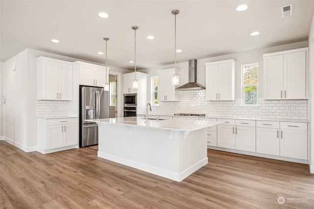 kitchen with white cabinetry, appliances with stainless steel finishes, sink, and wall chimney range hood