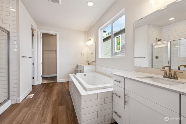 bathroom featuring hardwood / wood-style flooring, plus walk in shower, and vanity