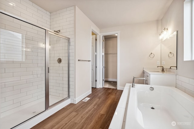 bathroom featuring hardwood / wood-style flooring, vanity, and plus walk in shower