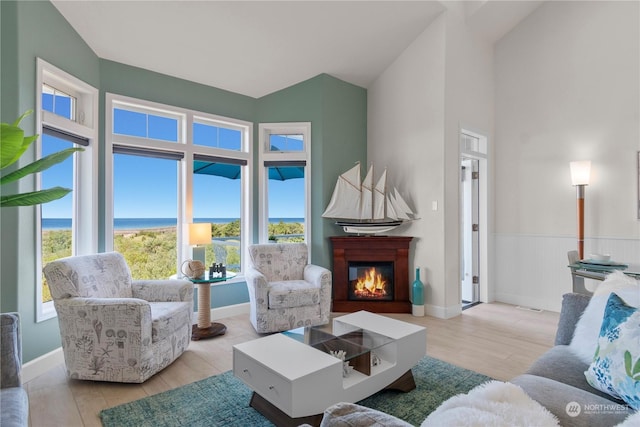 living room featuring a water view, vaulted ceiling, and light wood-type flooring