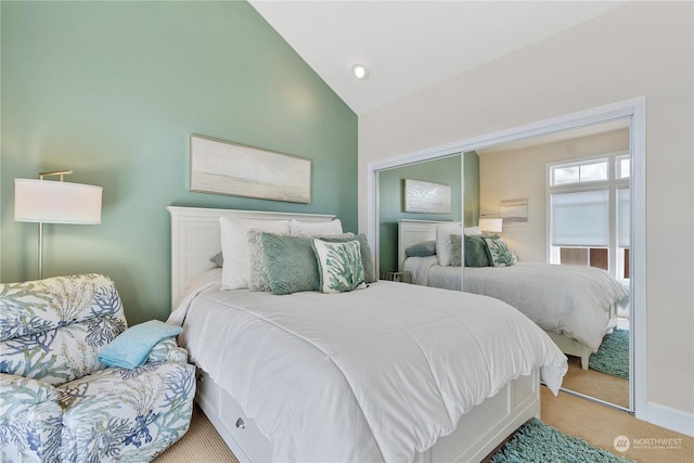 bedroom featuring light colored carpet, vaulted ceiling, and a closet