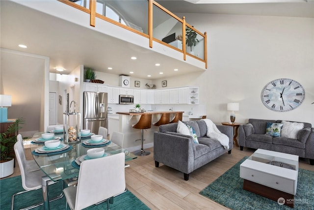 living room featuring high vaulted ceiling and light hardwood / wood-style floors