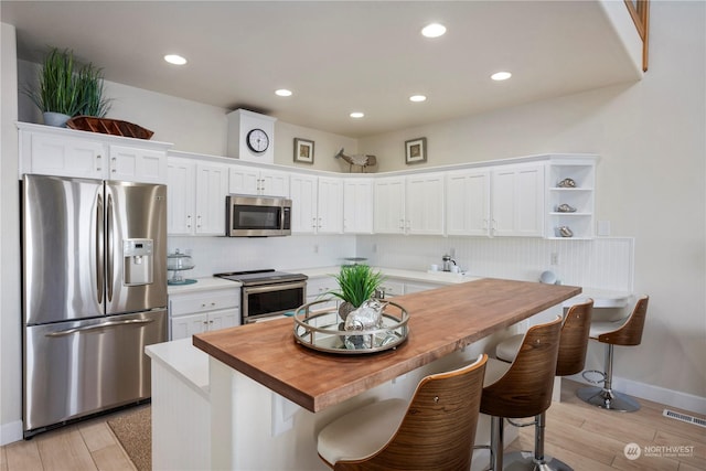 kitchen featuring stainless steel appliances, white cabinets, and a kitchen bar