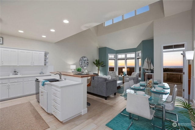 kitchen with white cabinetry, a kitchen island with sink, sink, and stainless steel dishwasher