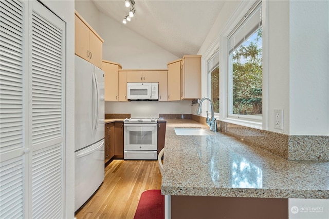 kitchen with cream cabinets, white appliances, a sink, light wood-style floors, and vaulted ceiling