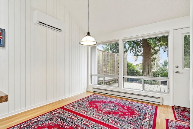 dining space featuring a baseboard heating unit, a wall mounted air conditioner, and wood finished floors