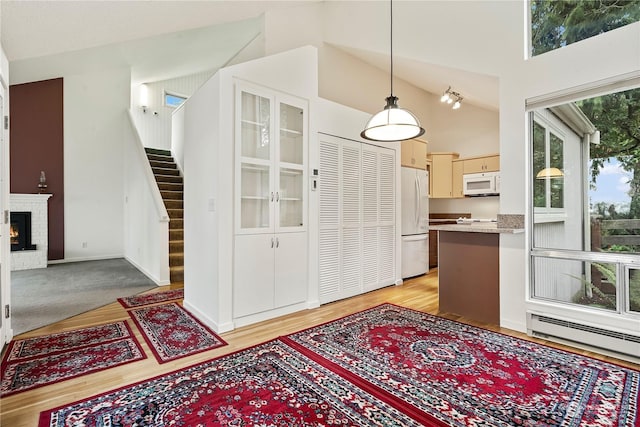 interior space with white appliances, decorative light fixtures, light countertops, a brick fireplace, and a baseboard heating unit