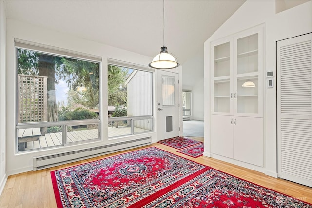 interior space featuring a healthy amount of sunlight, light wood-type flooring, a baseboard radiator, and lofted ceiling