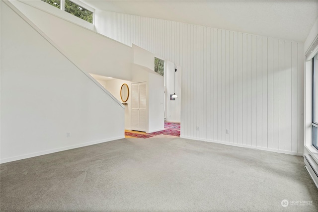 empty room with a baseboard heating unit, carpet flooring, and baseboards