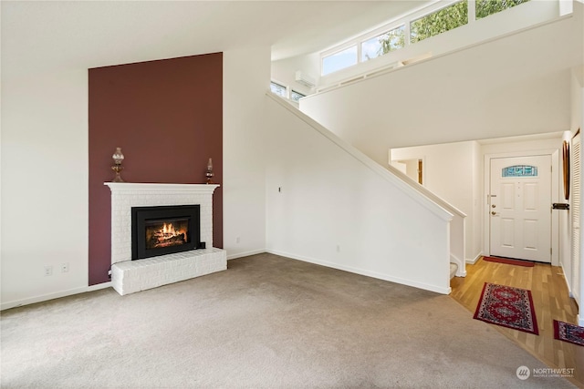 unfurnished living room featuring a towering ceiling, stairs, carpet floors, and a fireplace