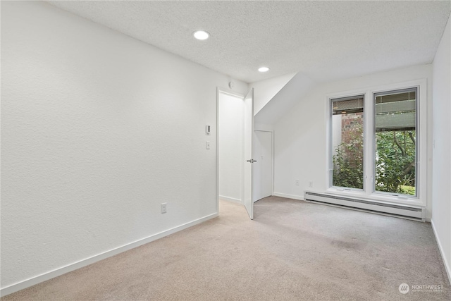 additional living space featuring carpet floors, baseboards, a baseboard heating unit, and a textured ceiling