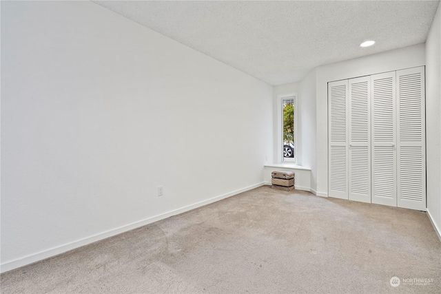 unfurnished bedroom with carpet, a closet, a textured ceiling, and baseboards