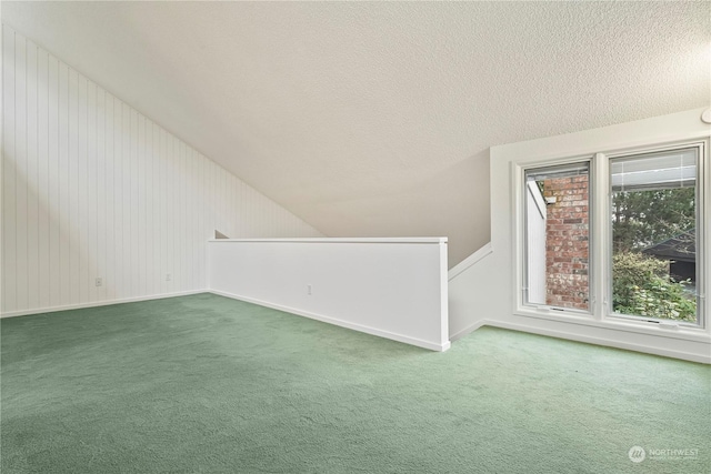 bonus room with a textured ceiling, vaulted ceiling, carpet, and baseboards