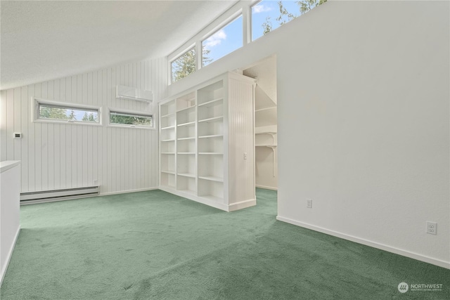 carpeted empty room with a baseboard heating unit, vaulted ceiling, and baseboards