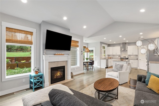 living room featuring plenty of natural light, lofted ceiling, and light hardwood / wood-style flooring