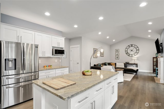 kitchen featuring white cabinetry, appliances with stainless steel finishes, light stone counters, and a kitchen island