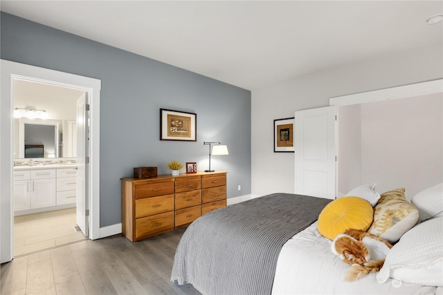 bedroom with connected bathroom and light wood-type flooring