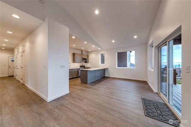 kitchen featuring lofted ceiling, sink, light hardwood / wood-style flooring, gray cabinets, and appliances with stainless steel finishes