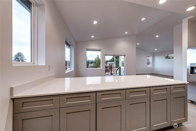 kitchen featuring gray cabinetry, vaulted ceiling, and kitchen peninsula