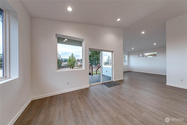 spare room featuring lofted ceiling and light hardwood / wood-style flooring