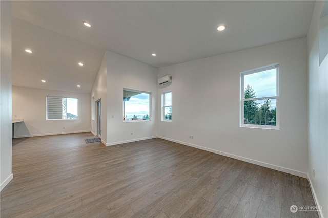 spare room with a wall mounted AC and light hardwood / wood-style flooring