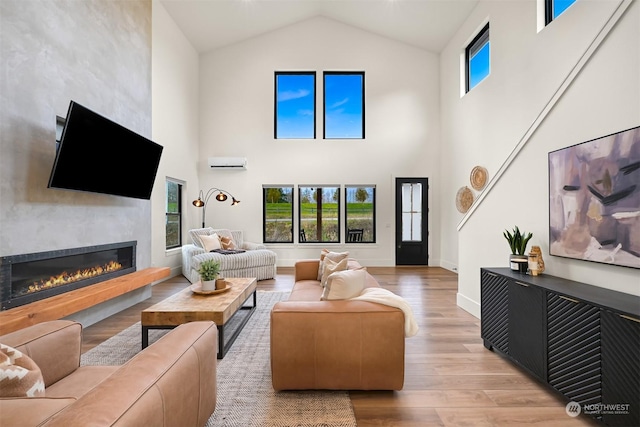 living room featuring high vaulted ceiling, a wall mounted AC, and light hardwood / wood-style floors