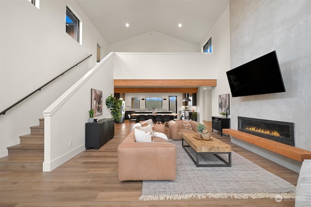 living room with a towering ceiling and light hardwood / wood-style flooring