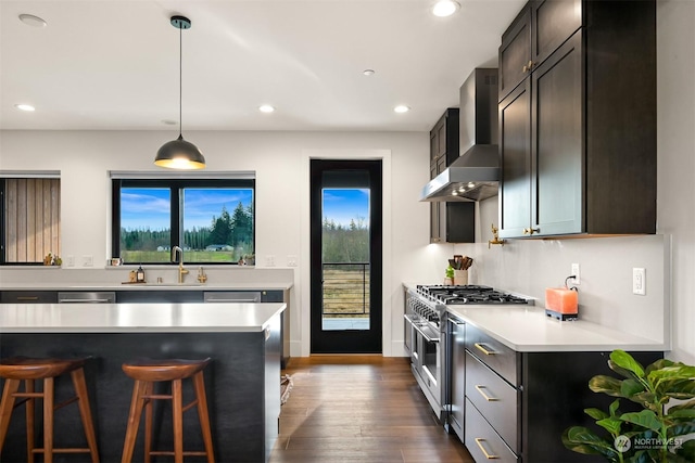 kitchen featuring pendant lighting, wall chimney range hood, sink, dark wood-type flooring, and high end range