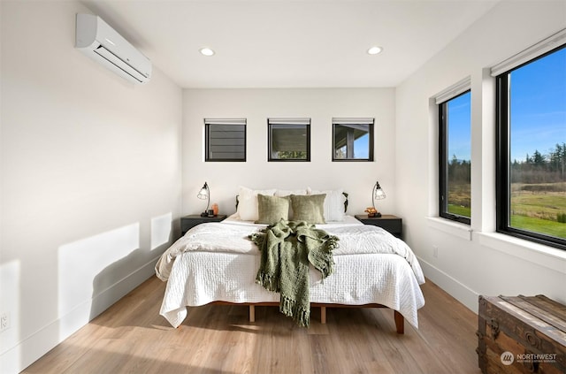 bedroom with a wall unit AC and light wood-type flooring