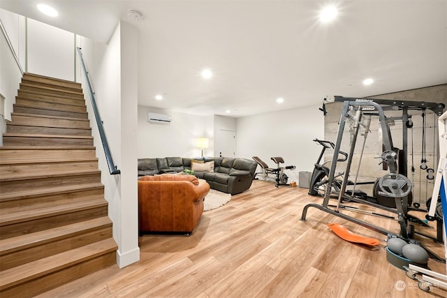 exercise room with light hardwood / wood-style flooring and an AC wall unit