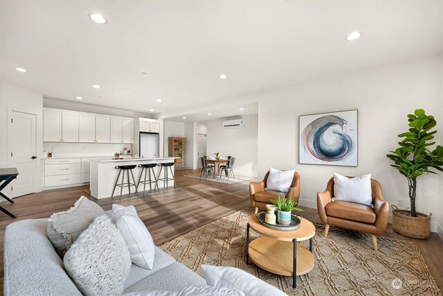 living room featuring sink, hardwood / wood-style flooring, and a wall unit AC