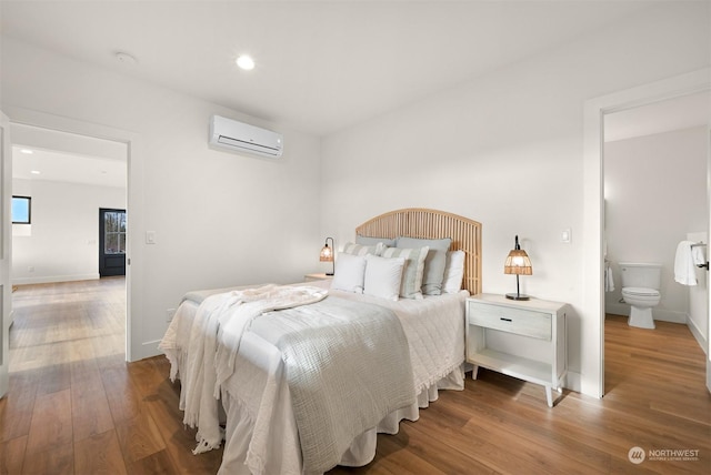 bedroom featuring hardwood / wood-style floors and a wall unit AC