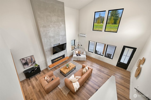 living room with high vaulted ceiling, a tiled fireplace, and hardwood / wood-style floors