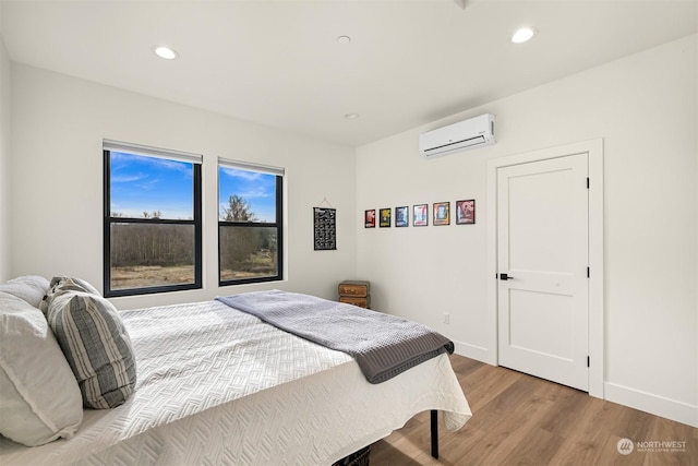 bedroom featuring hardwood / wood-style flooring and a wall mounted AC