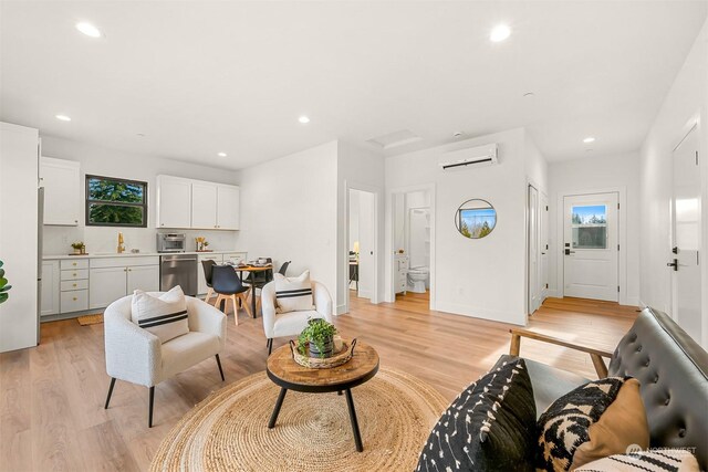 living room with a wall mounted AC and light hardwood / wood-style floors