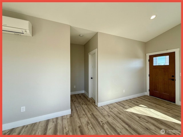 entrance foyer with vaulted ceiling, a wall mounted AC, and light hardwood / wood-style floors