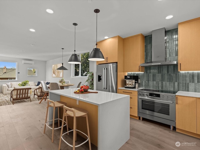 kitchen with wall chimney range hood, backsplash, stainless steel appliances, a wall mounted AC, and decorative light fixtures