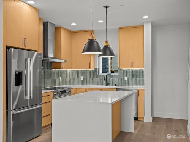 kitchen with a kitchen island, light brown cabinetry, hanging light fixtures, high end appliances, and wall chimney range hood