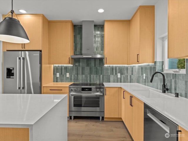 kitchen featuring pendant lighting, light brown cabinetry, sink, stainless steel appliances, and wall chimney range hood