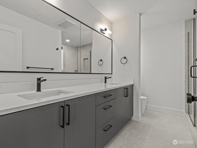 bathroom featuring vanity, a shower with shower door, and toilet