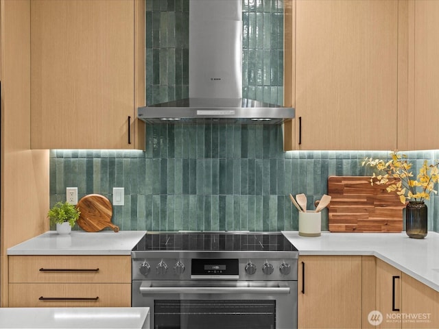 kitchen with light brown cabinetry, decorative backsplash, stainless steel range, and wall chimney exhaust hood