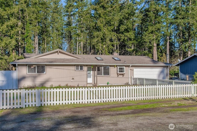 ranch-style home with a fenced front yard and a garage