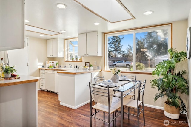 kitchen featuring wood finished floors, dishwasher, white cabinets, and light countertops