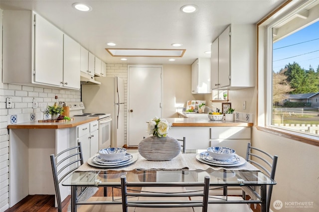 kitchen with under cabinet range hood, decorative backsplash, recessed lighting, white electric range oven, and white cabinetry