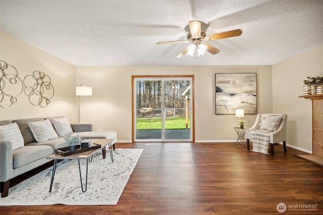 living area with baseboards, a textured ceiling, wood finished floors, and a ceiling fan