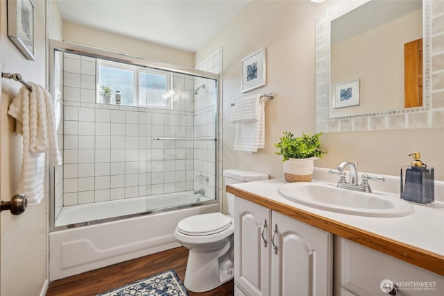 full bath featuring vanity, toilet, wood finished floors, and shower / bath combination with glass door