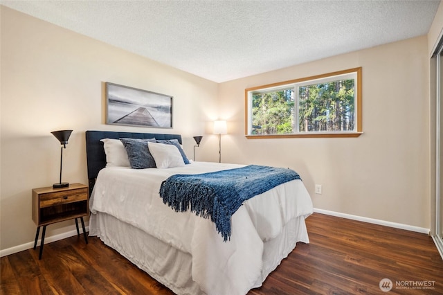 bedroom with a textured ceiling, baseboards, and wood finished floors