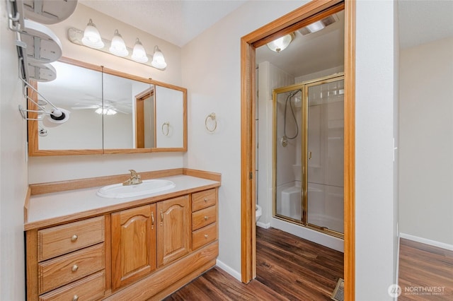 bathroom with visible vents, toilet, wood finished floors, and a stall shower