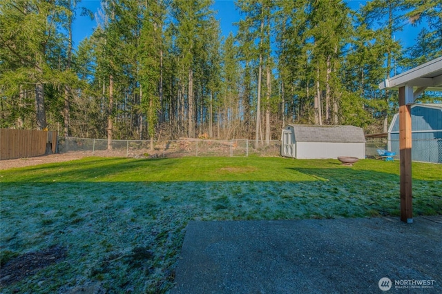 view of yard with a storage unit, an outbuilding, and fence